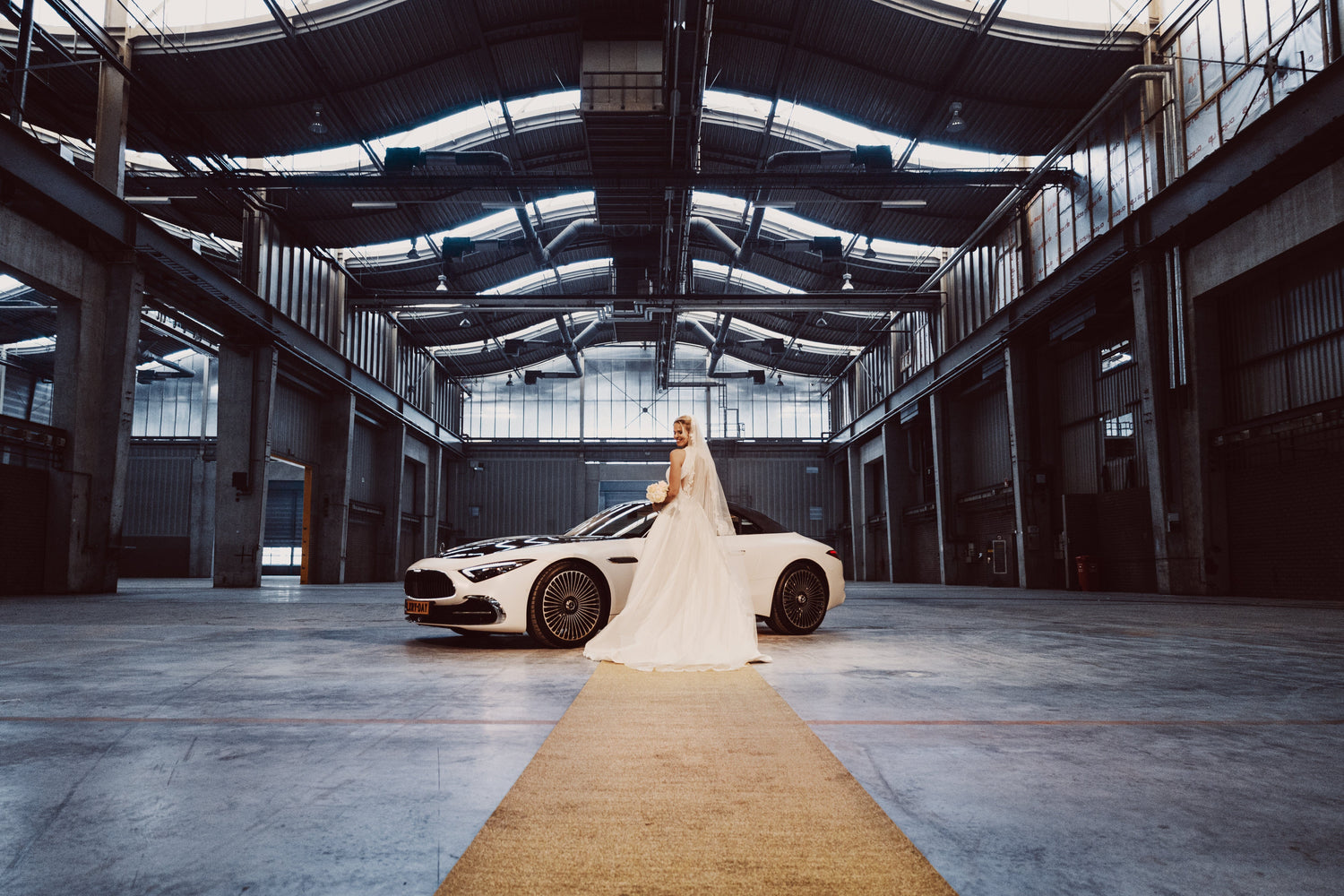Bruidspaar bij een luxe trouwauto op een gouden glitterloper
