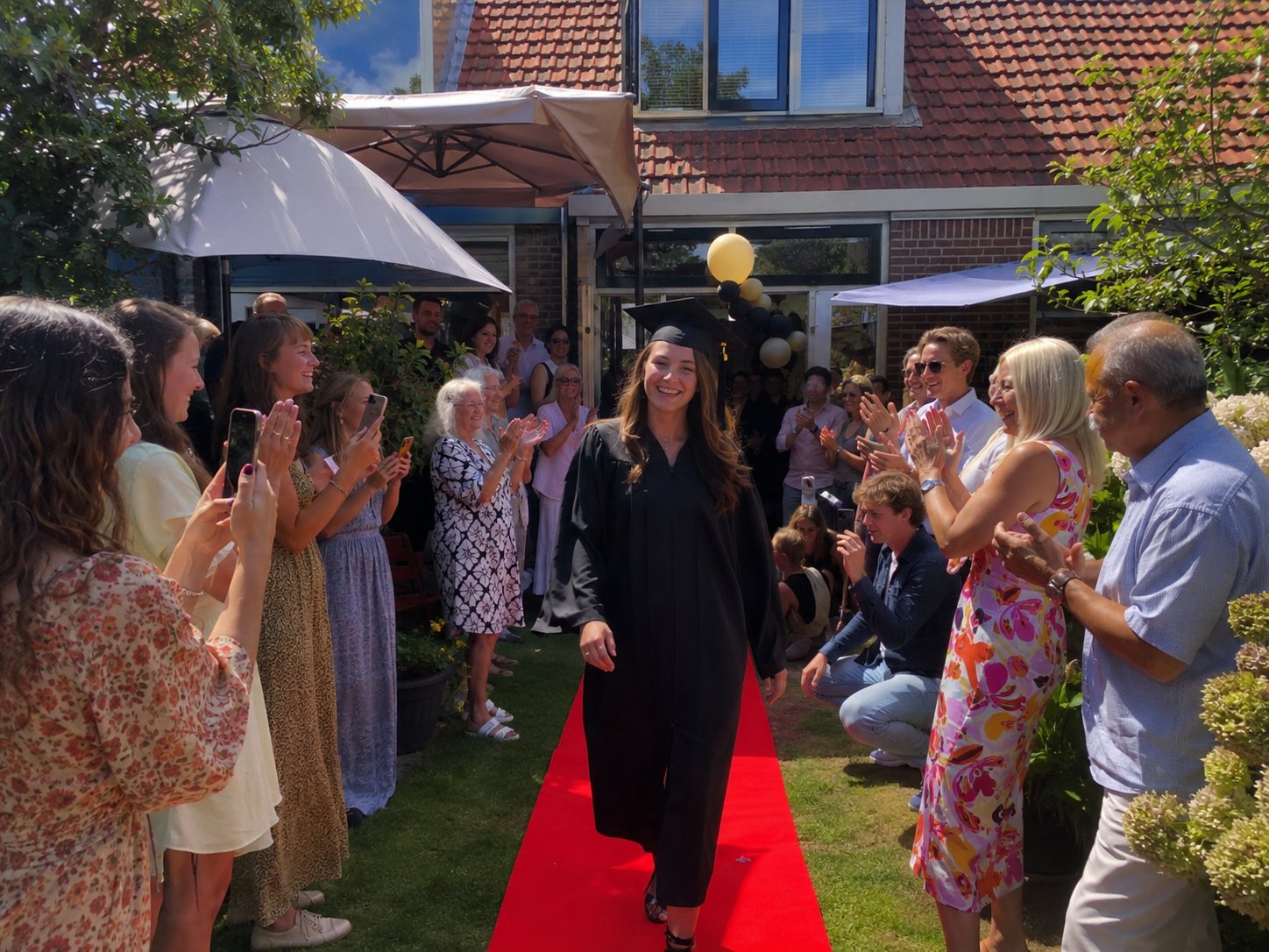 Geslaagde loopt over de rode loper door de tuin tijdens het slagingsfeest