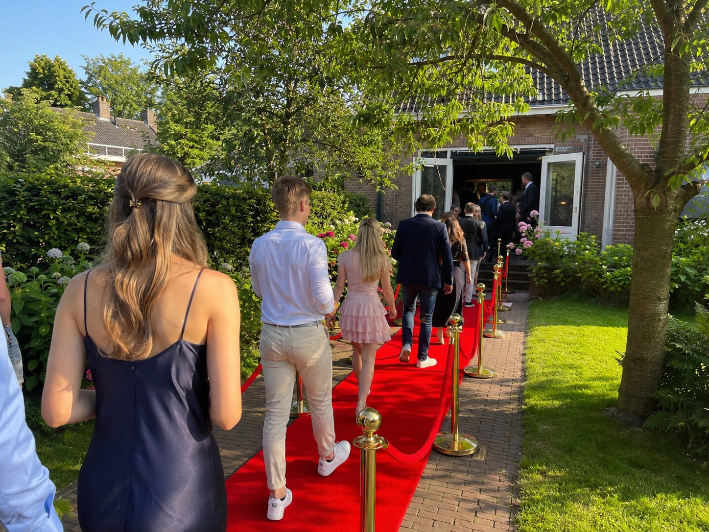 Rode loper met afzetpalen en koorden bij de entree van een slagingsfeest thuis