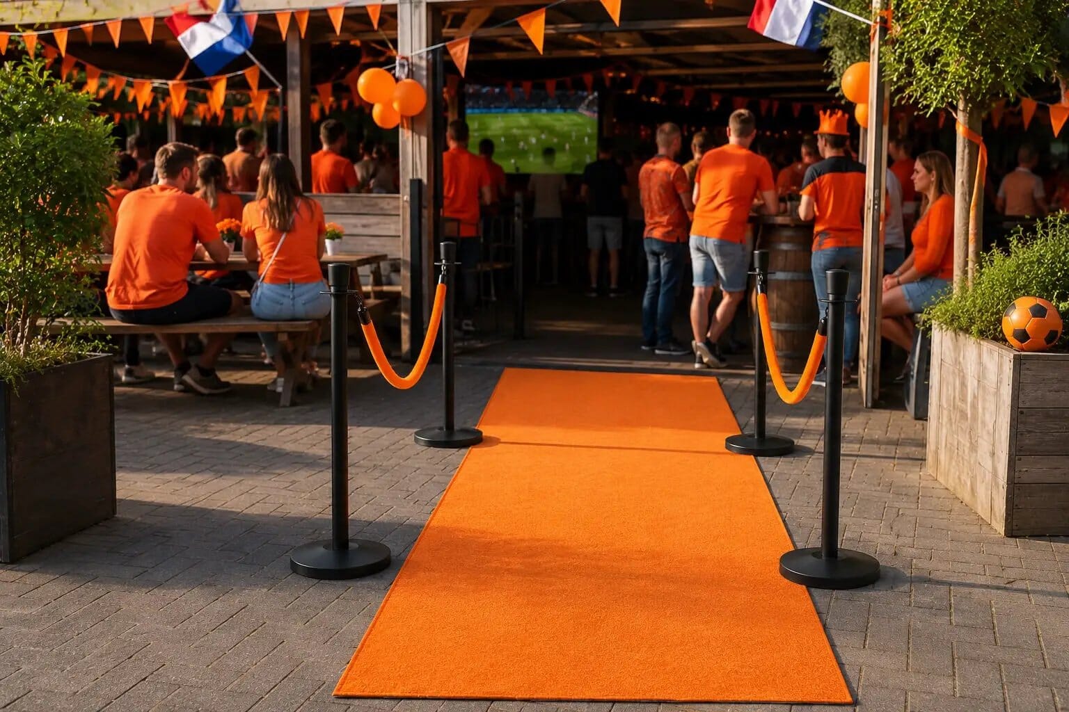 WK Oranje Leeuwen Bundel Outdoor: orange carpet walkway with black stanchions and orange ropes, crowd in orange shirts.